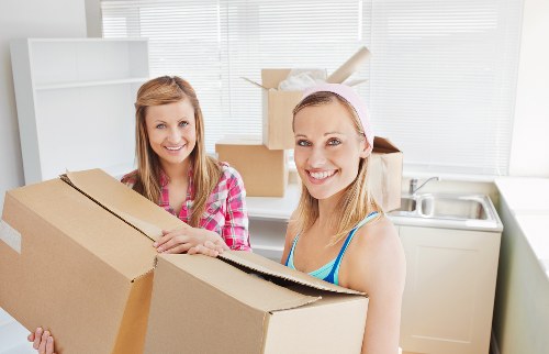 Professional movers carrying furniture through a London flat entrance
